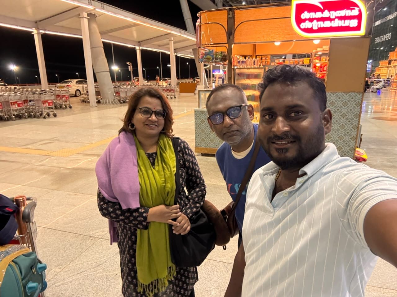 Skanda driver with a couple and their luggage trolley at Chennai airport at night